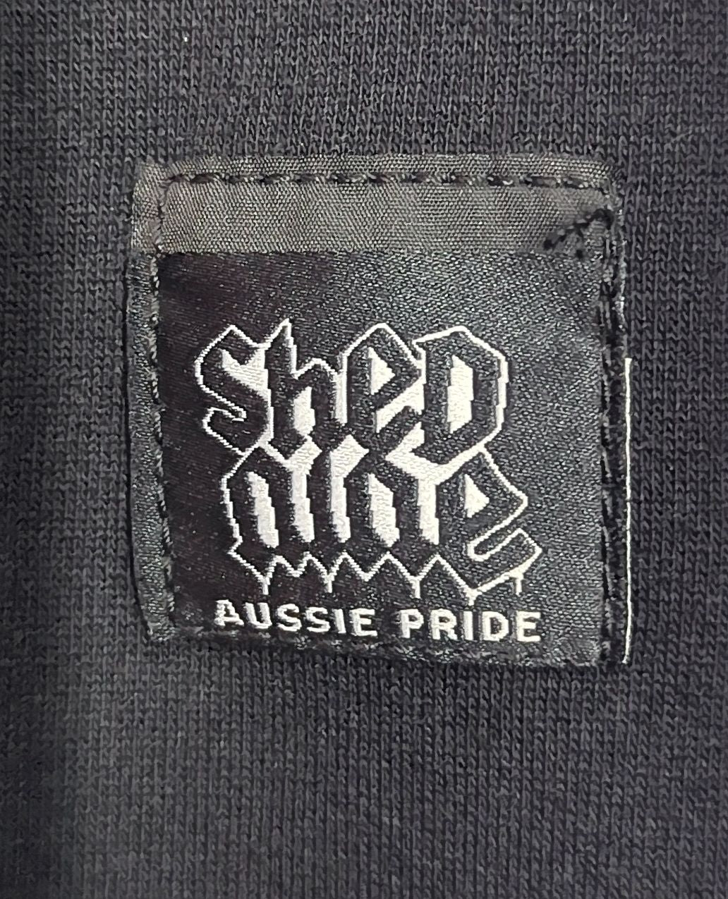 Label with 'Shed Nine' and 'Aussie Pride' text on a dark fabric background