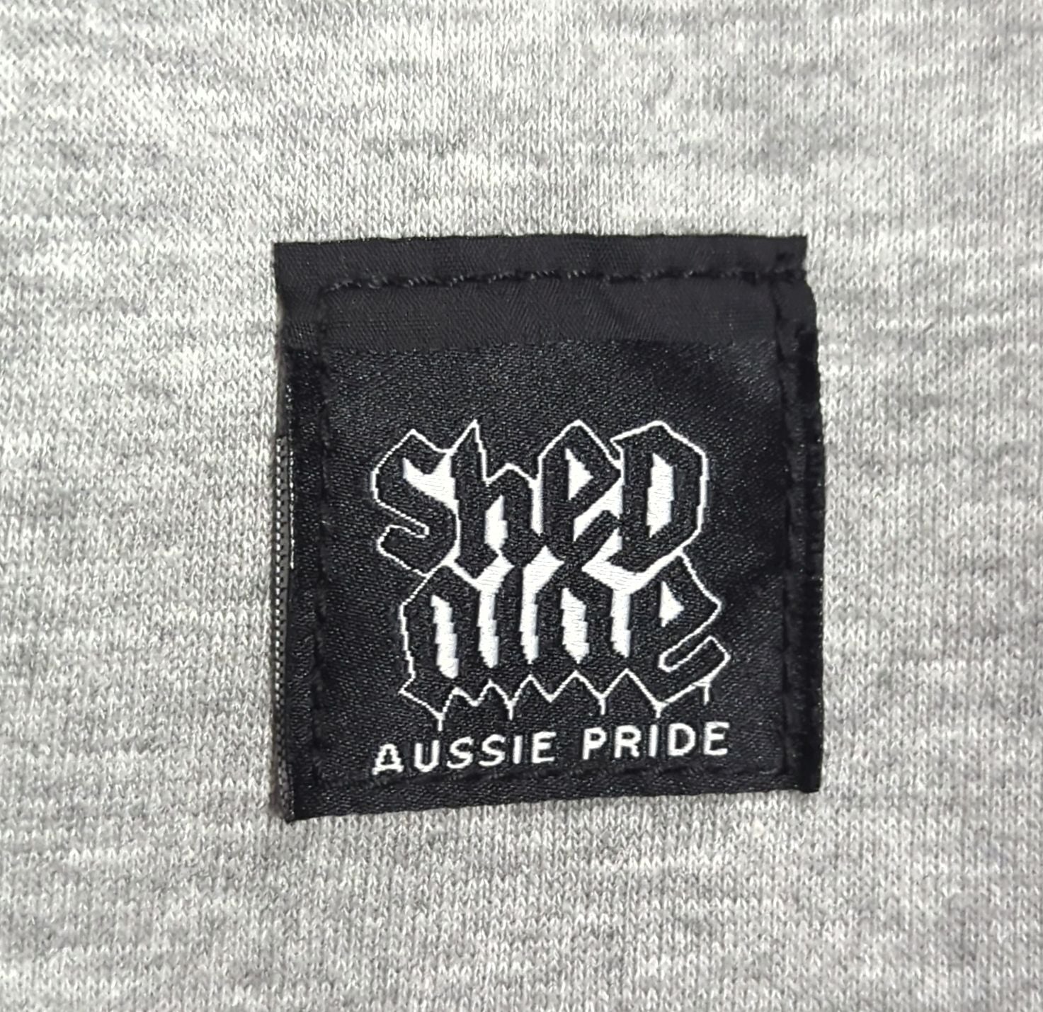 Black label with 'Shed One' and 'Aussie Pride' text on a gray fabric background