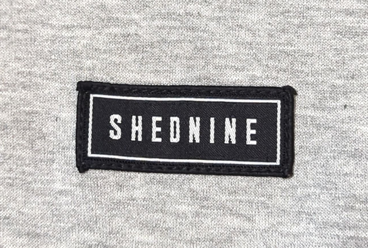 Black patch with 'SHEDNINE' text on a gray fabric background