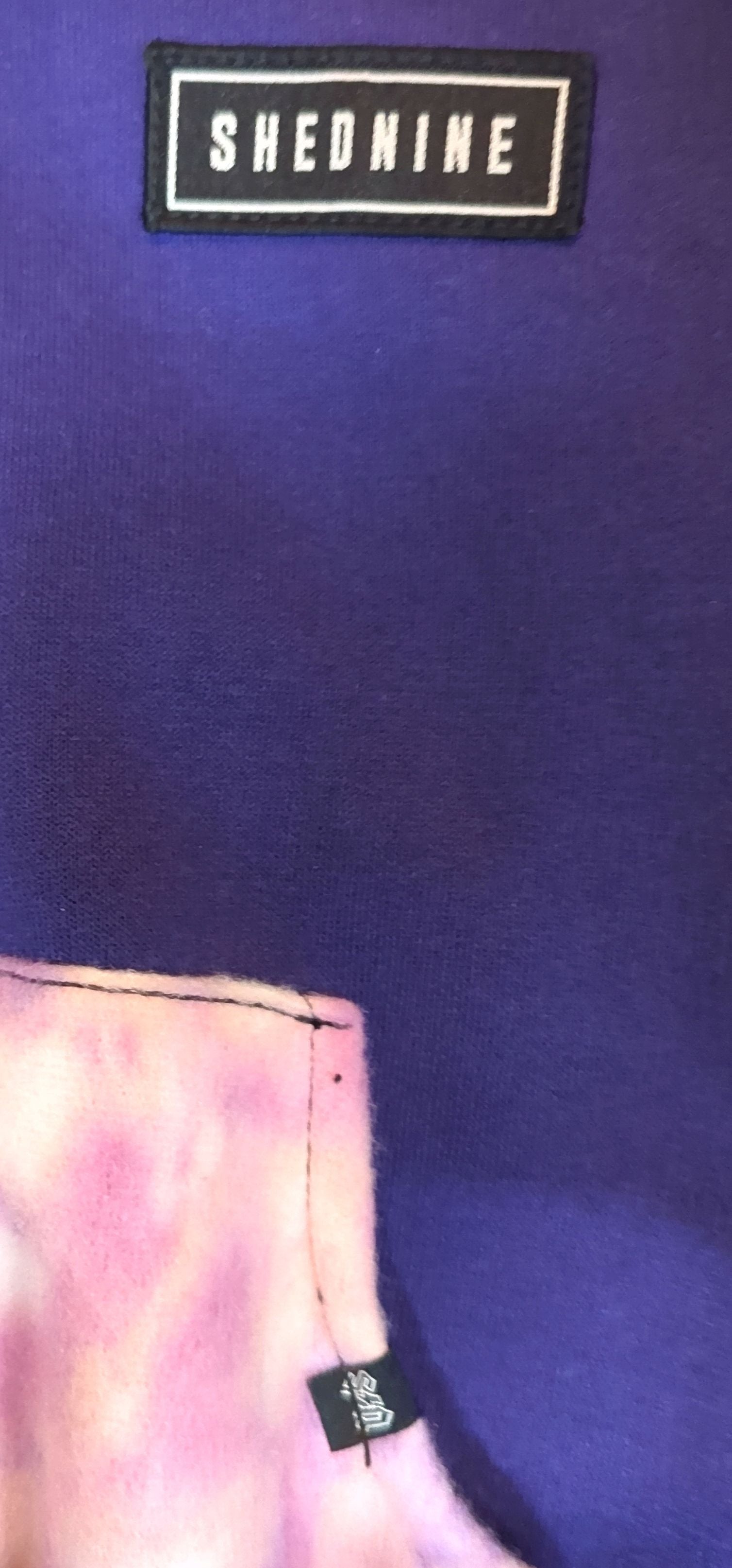 Close-up of a purple garment with 'SHEDMINE' branding.