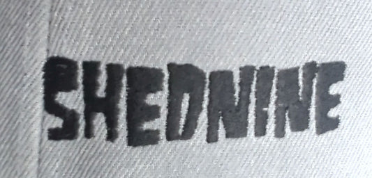 Text 'SHEDNINE' embossed on a textured surface