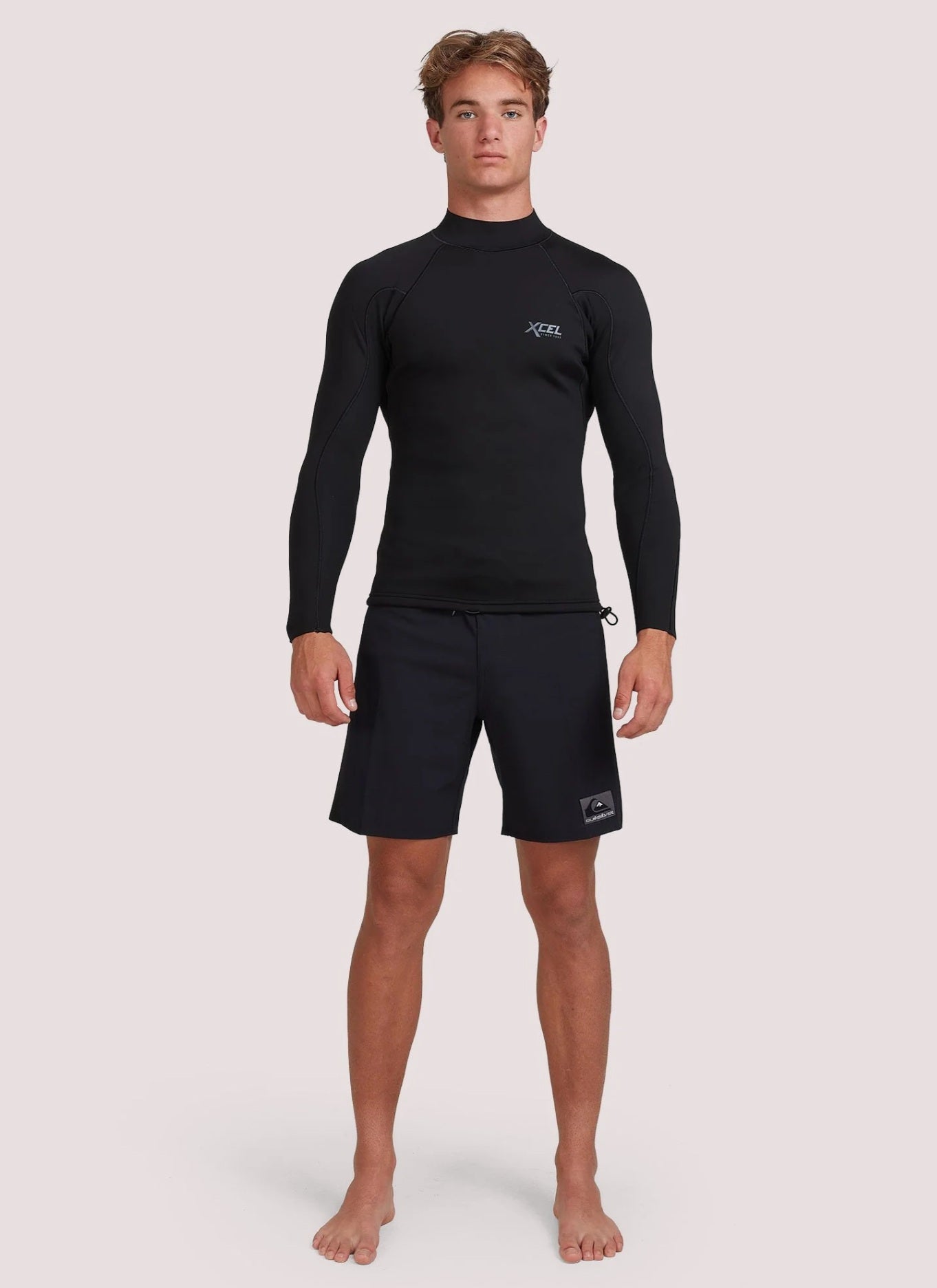 Man wearing a black long-sleeve rash guard and shorts on a white background