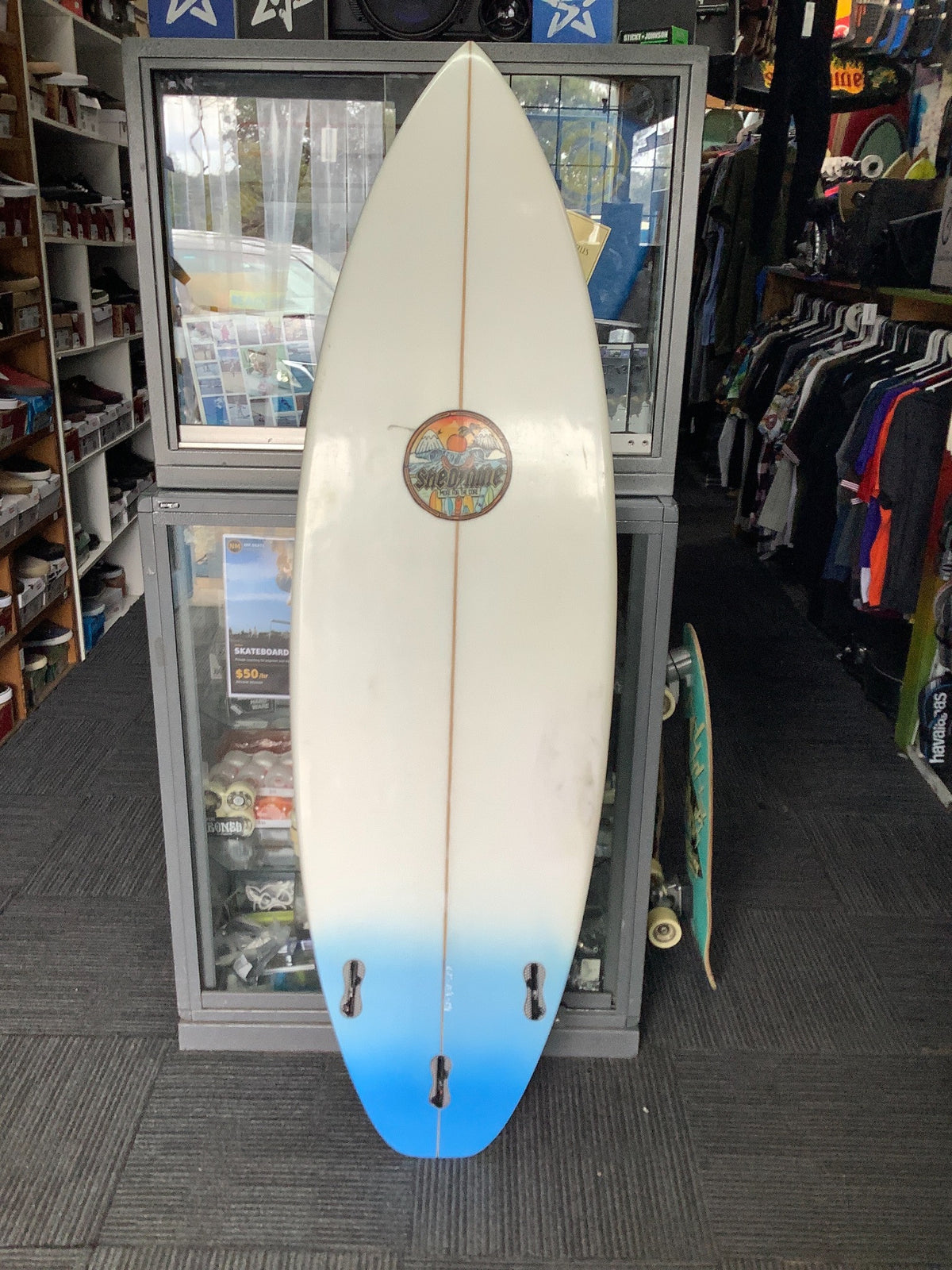 Bottom view of used Shed 9 Custom 6'2 surfboard with Shed Nine logo, blue tail and empty fin boxes