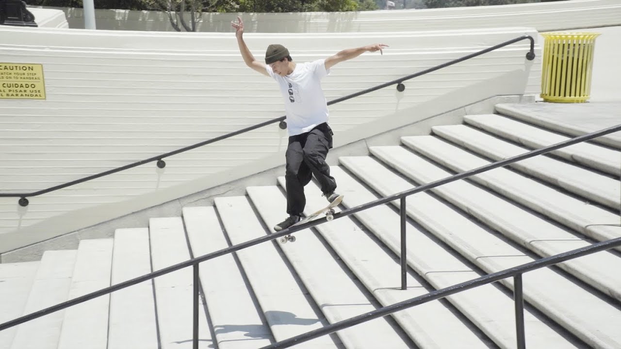 Person skateboarding down a set of stairs with a white wall and yellow caution sign in the background.