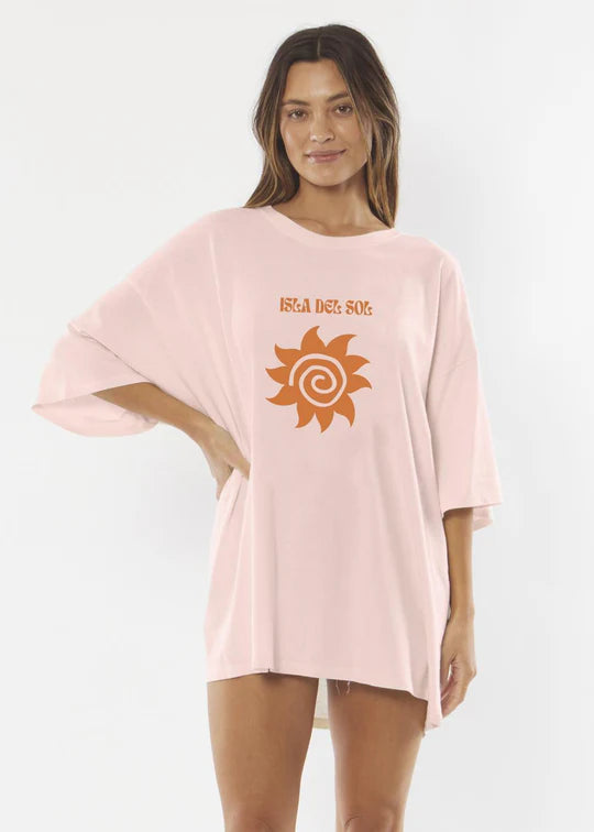 Woman wearing a pink oversized t-shirt with a sun graphic and text on a white background SHED NINE