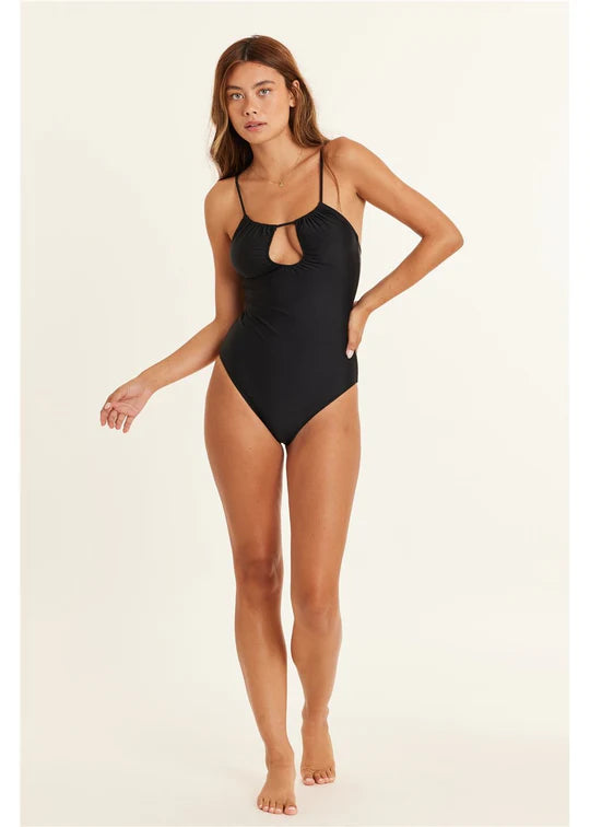 Woman wearing a black swimsuit on a beige background SHED NINE