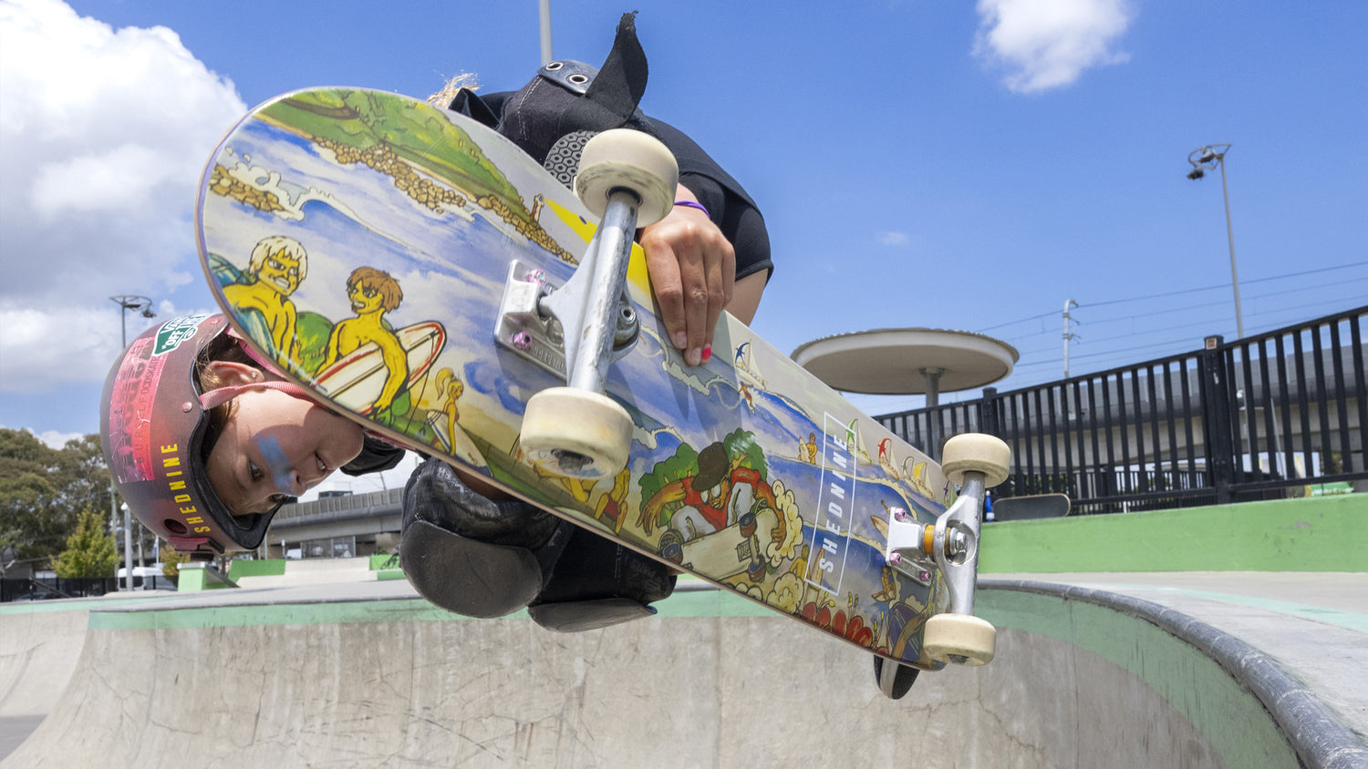 Person skateboarding with a colorful skateboard at a skate park.