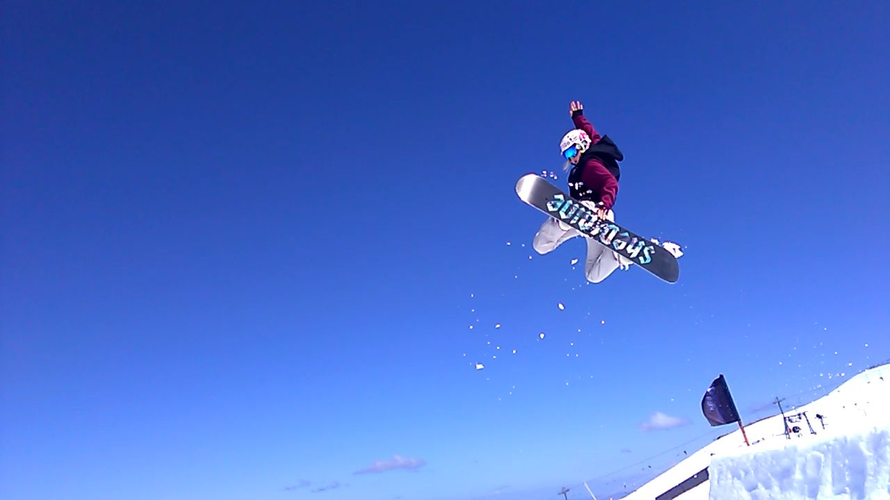 Person snowboarding in the air against a clear blue sky