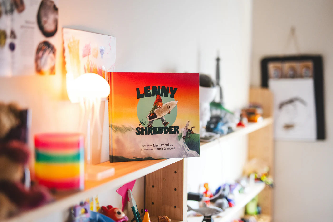 Book titled 'Lenny the Shredder' on a shelf with colorful objects in the background shed nine