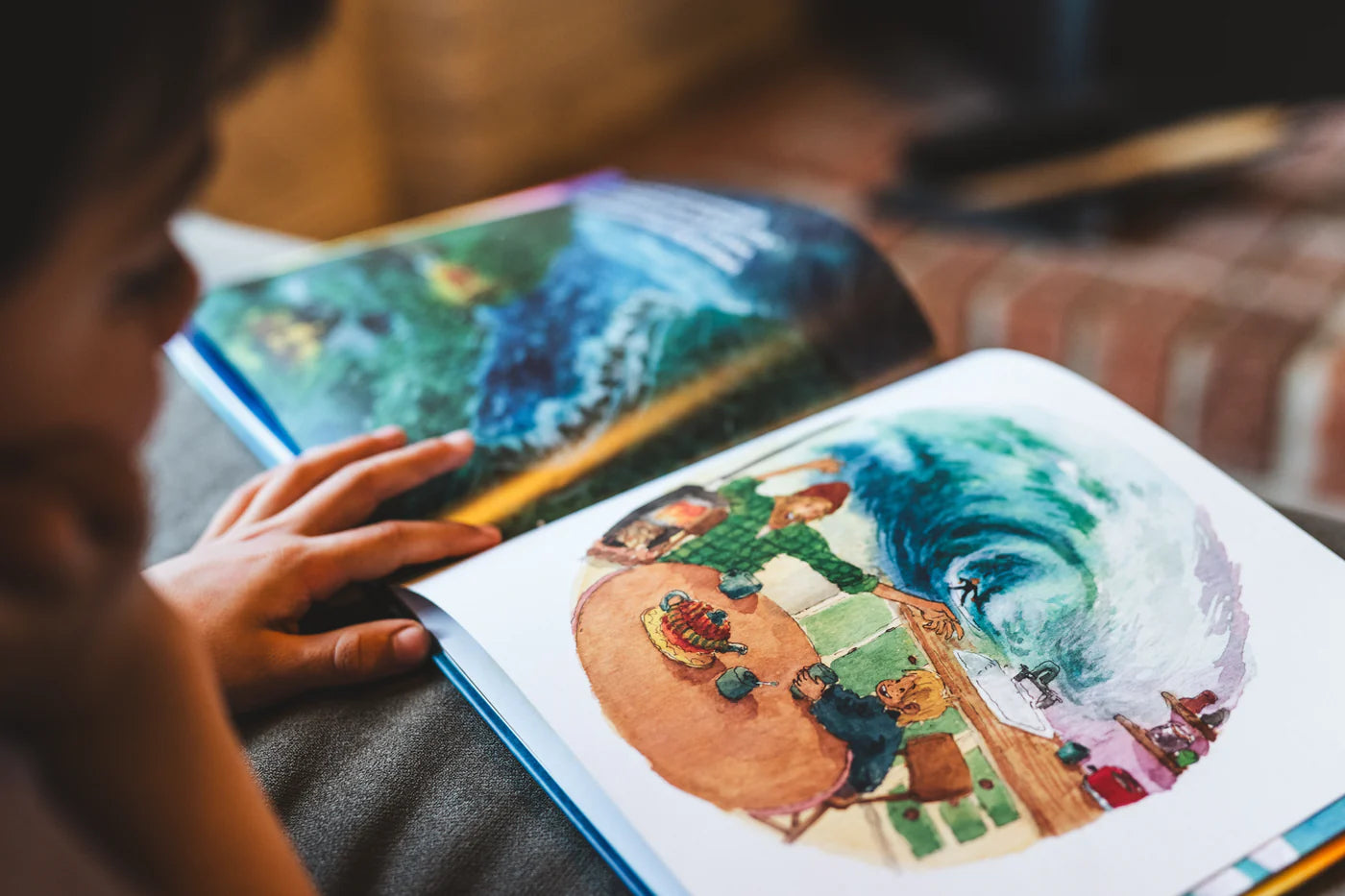 Person holding a book with colorful illustrations of a landscape and people. shed nine