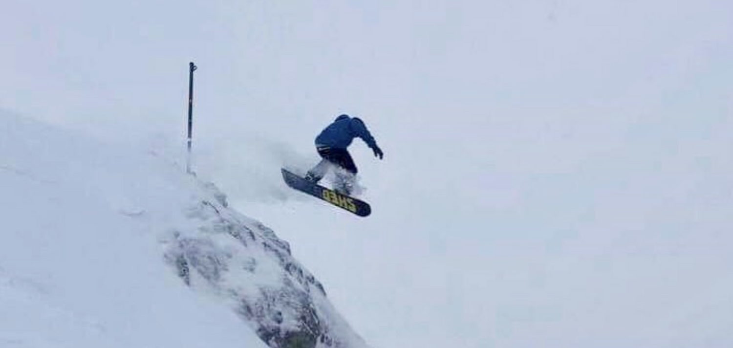 Person snowboarding down a steep slope on a snowy day
