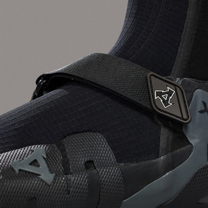 Close-up of a black and gray sneaker with a brand logo on a gray background shed nine