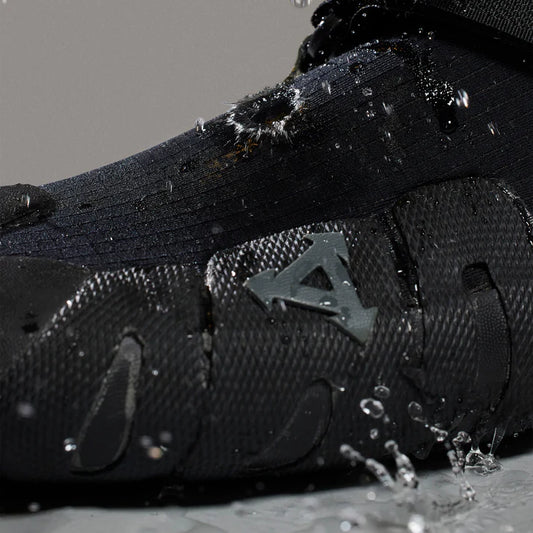 Black shoe with brand logo splashing in water on a gray background shed nine