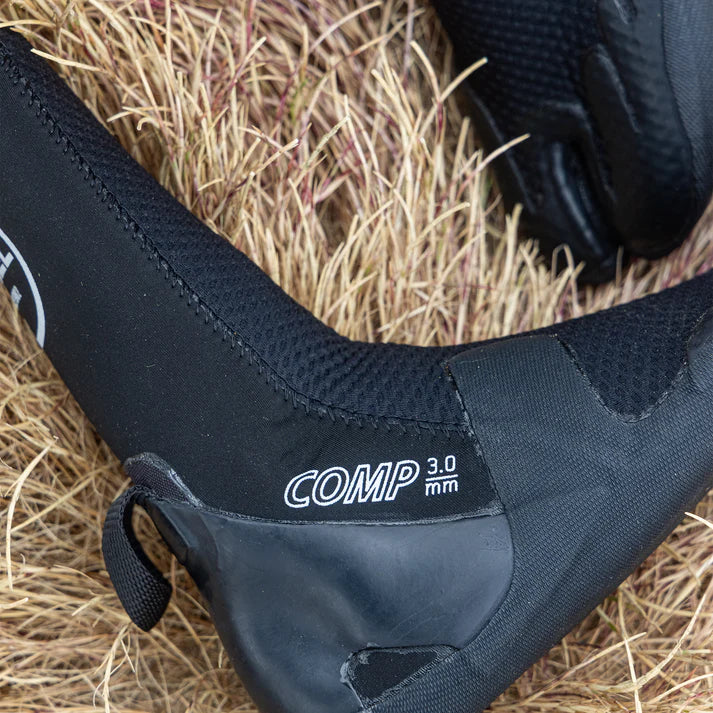 Close-up of a black watercraft boot with 'COMP 3.0 mm' text on a grassy background shed nine