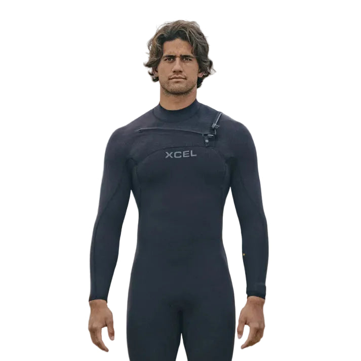 Man wearing an XCEL wetsuit on a beach with mountains in the background shed nine