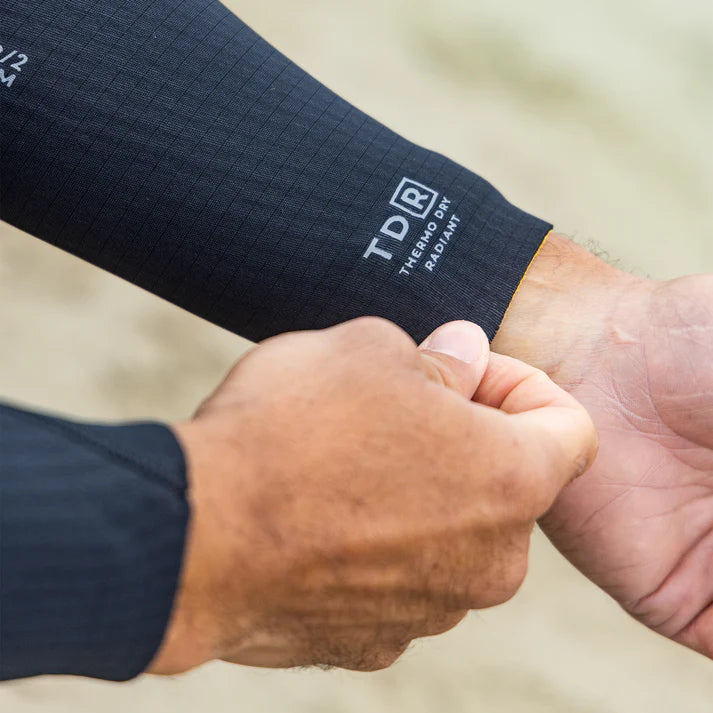 Close-up of a person wearing a navy blue sleeve with 'TD&R' branding, holding hands. shed nine
