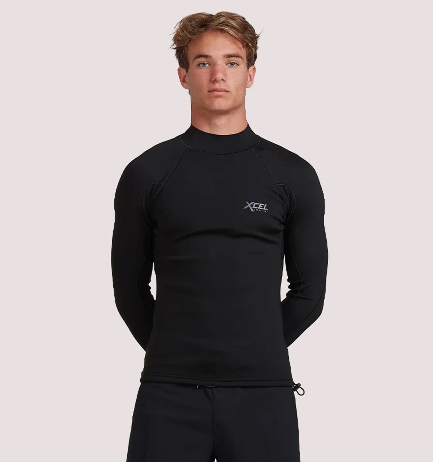 Person wearing a black XCEL wetsuit on a light pink background