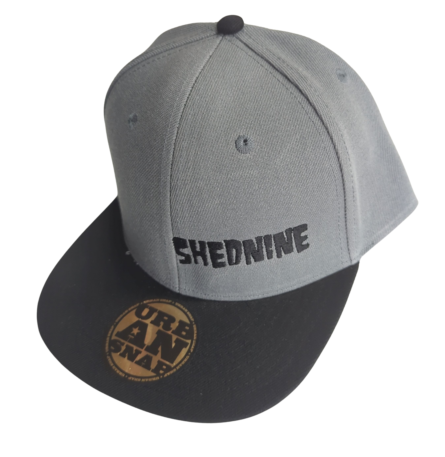 Gray and black cap with 'SHEDNINE' branding on a white background
