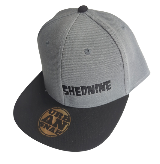 Gray and black cap with 'SHEDNINE' branding on a white background
