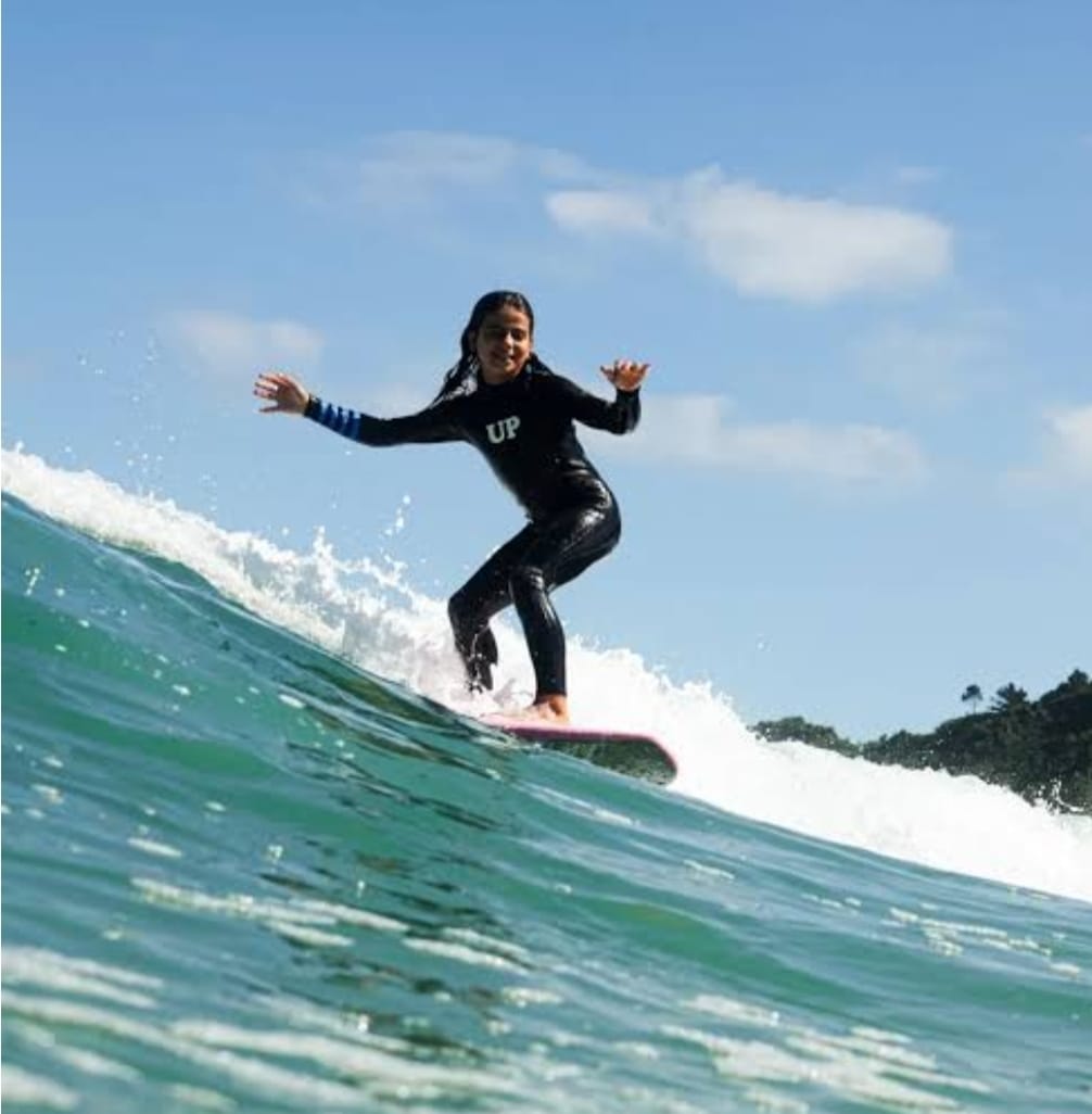 Person surfing on a wave with a clear blue sky in the background