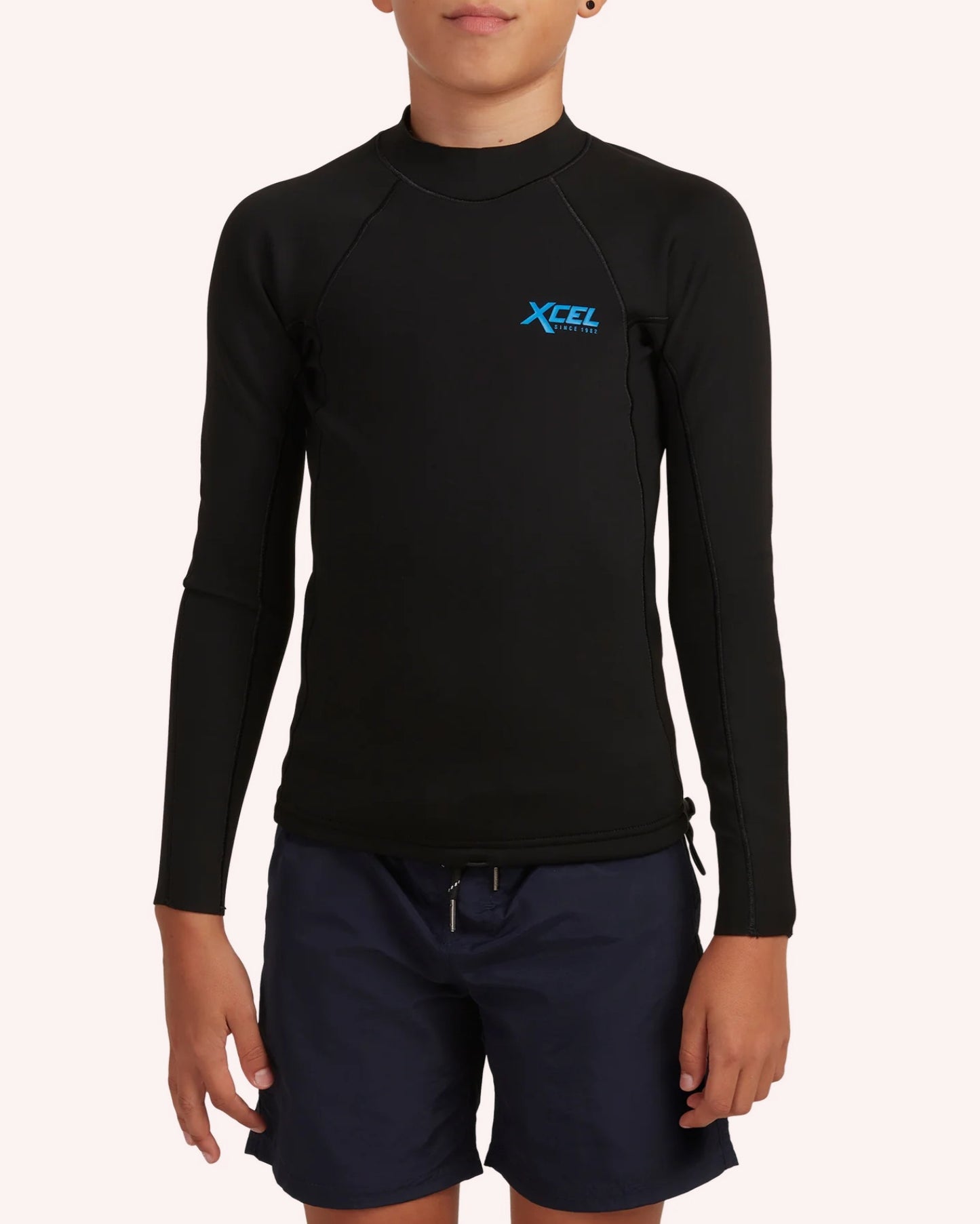 Person wearing a black long-sleeve rash guard with XCEL logo on a white background