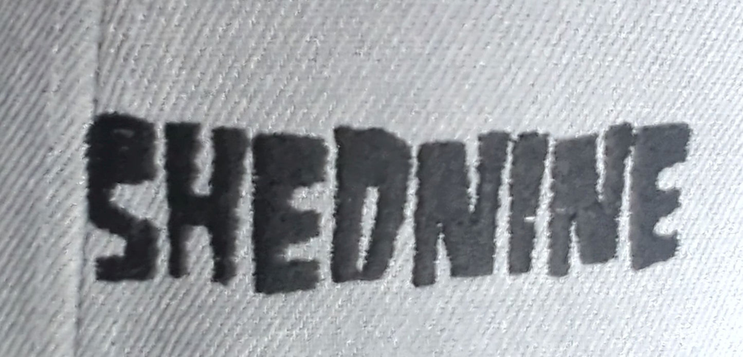 Text 'SHEDNINE' embossed on a textured surface