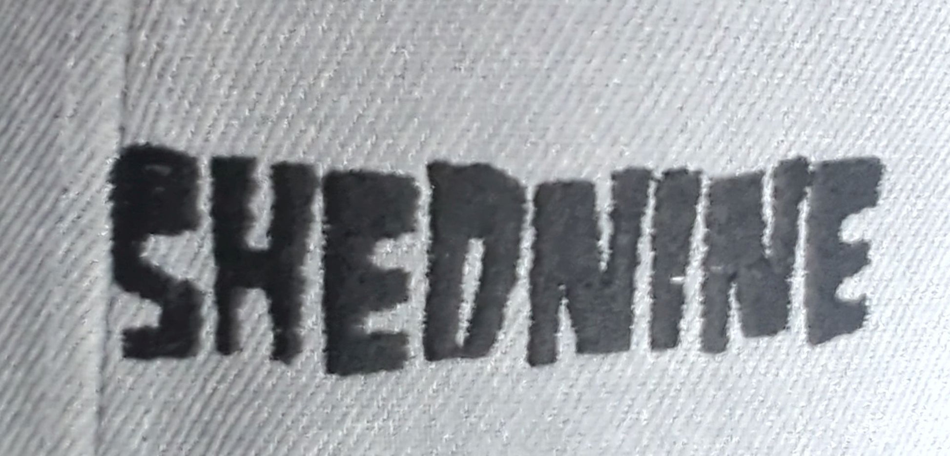 Text 'SHEDNINE' embossed on a textured surface
