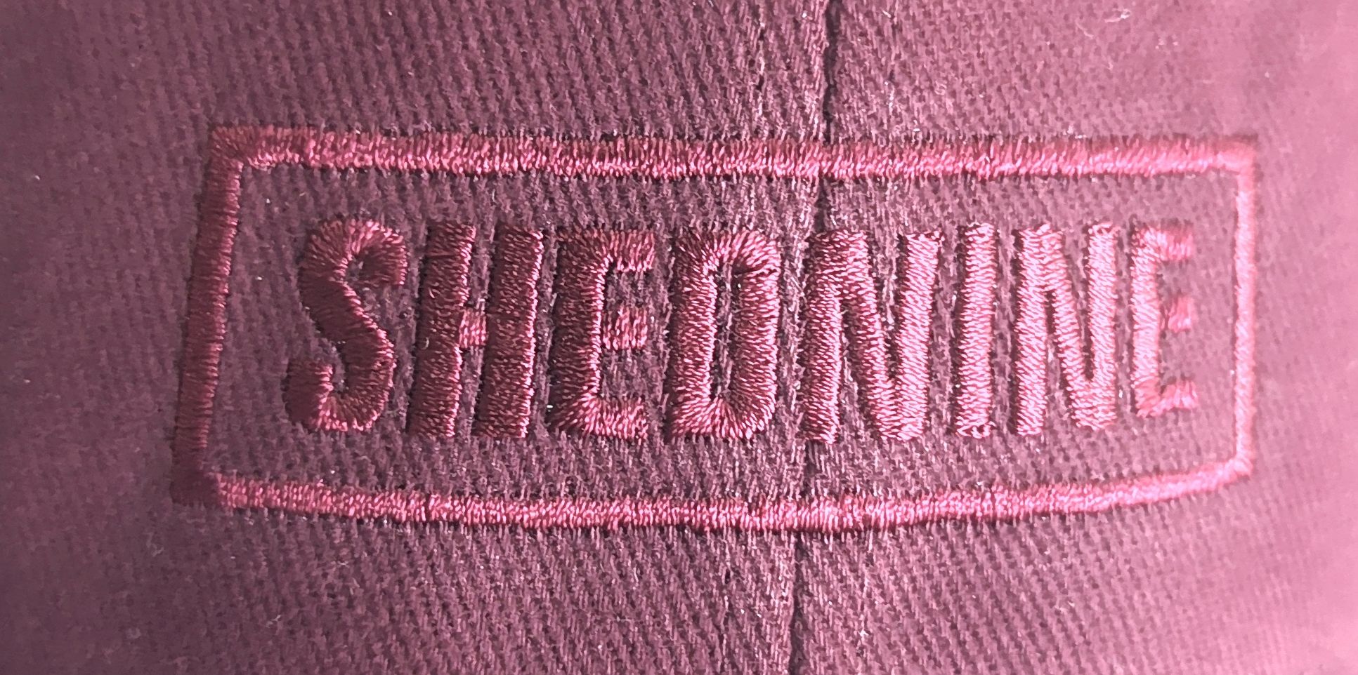 Close-up of a pink cap with 'SHEDNINE' embroidered on it.
