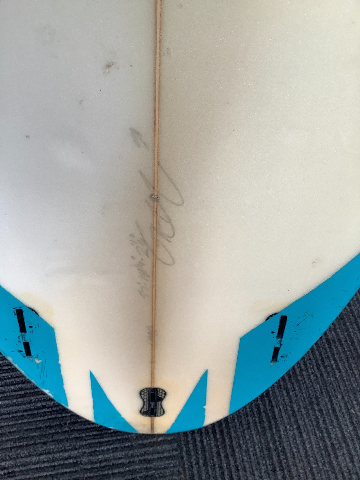 Close-up of used PISC surfboard tail, fin boxes and faint handwritten markings
