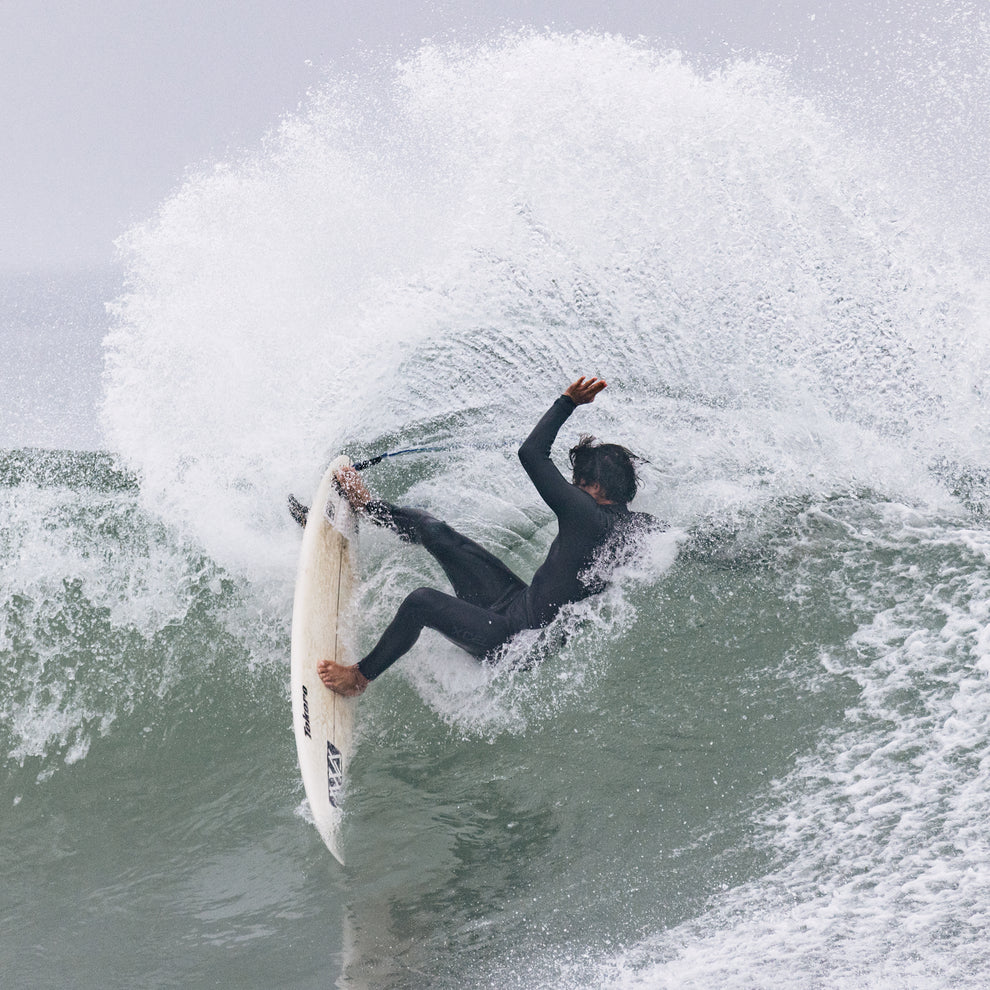 Surfer wearing Xcel Men’s Comp 3/2mm Chest Zip Steamer Wetsuit in black in the water