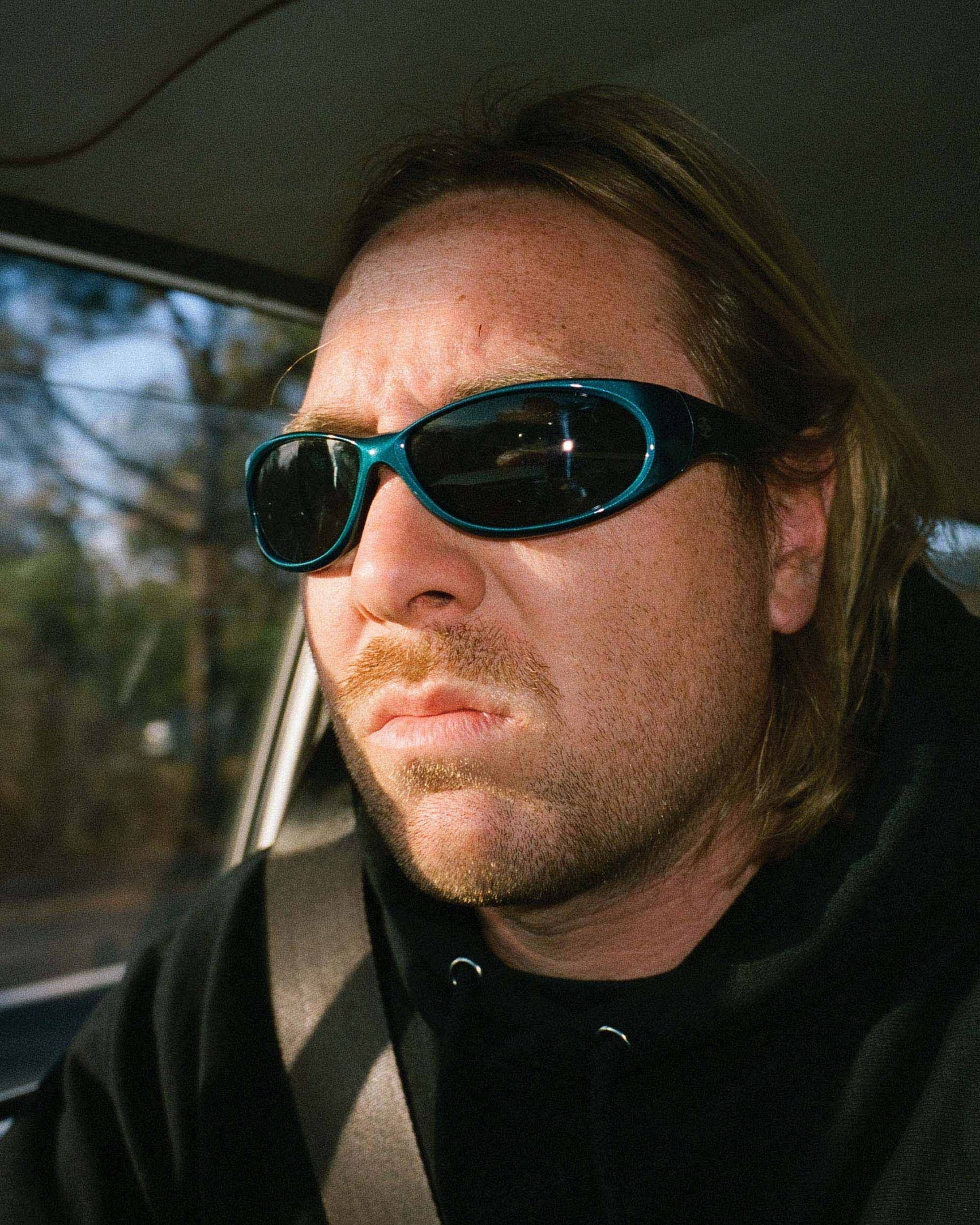 Lifestyle image of model wearing Ritual Vision Demon Speed Sunglasses in Matte Chrome / Blue Reflective Polarised 65 mm while driving shed nine