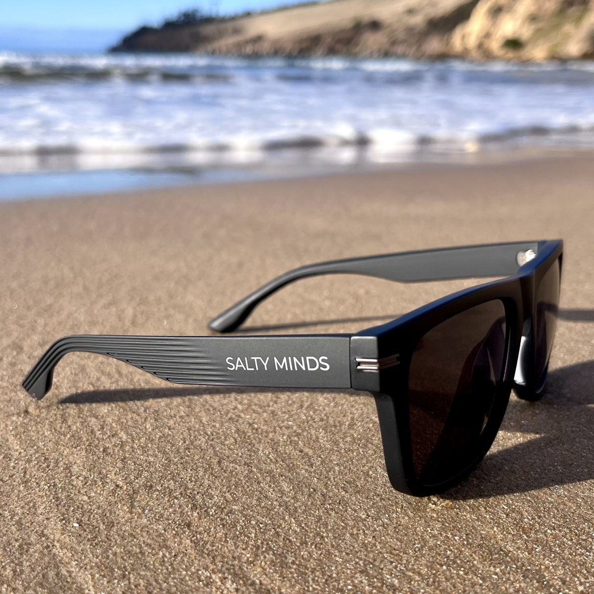Salty Minds Pedra black sunglasses on the beach