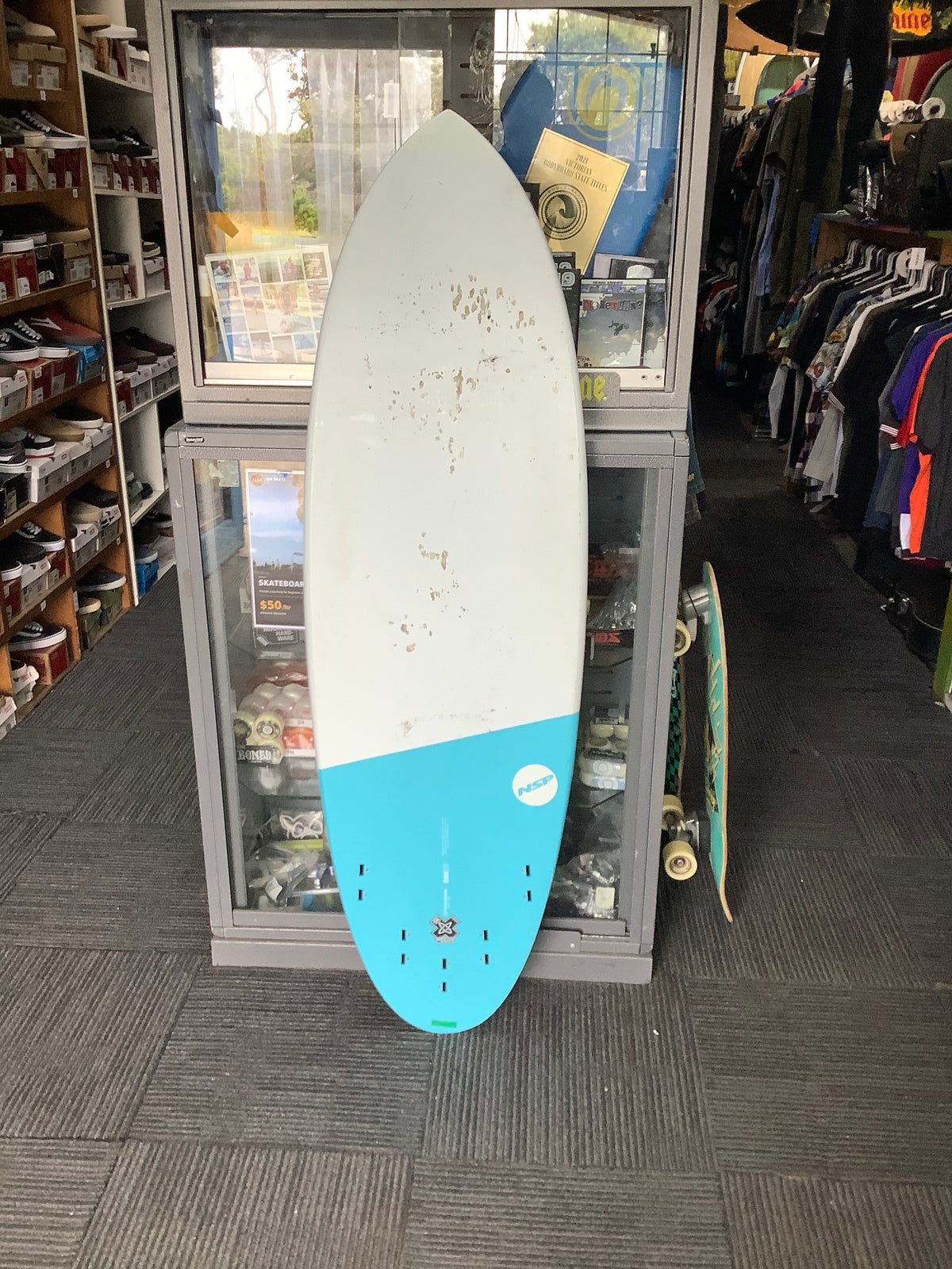Second-hand NSP Hybrid blue and white surfboard underside showing marks and five-fin-box setup