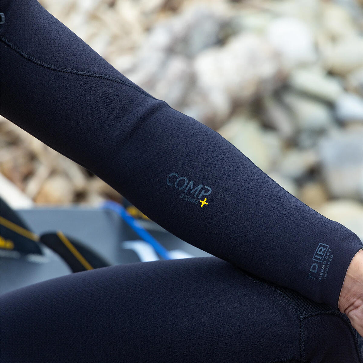 Close-up of a person wearing black compression sleeves with visible branding against a blurred natural background. shed nine 