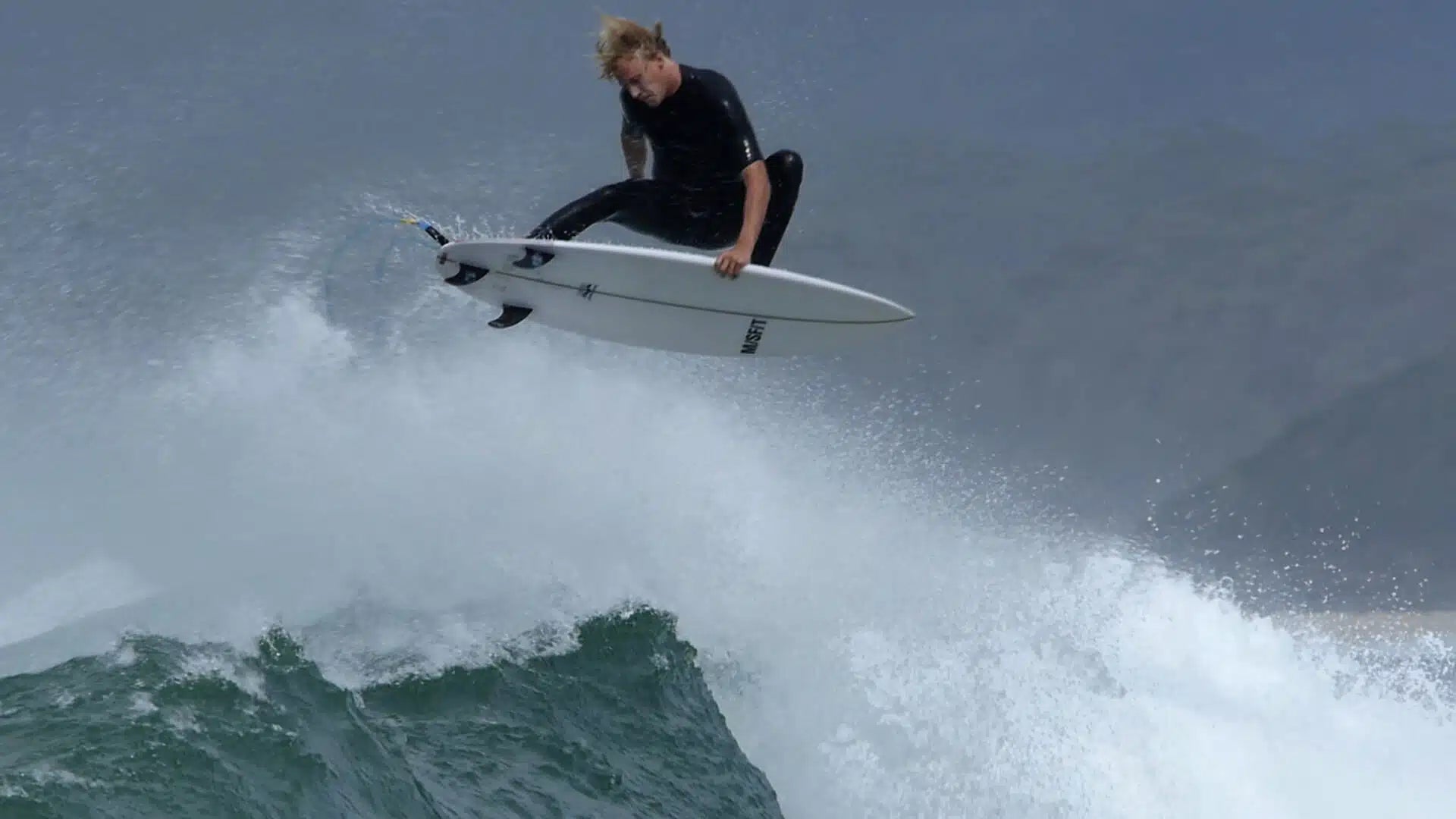 Surfer riding a wave wearing Zion Wesley 2/2mm GBS Long Arm Springsuit Wetsuit in black shed nine